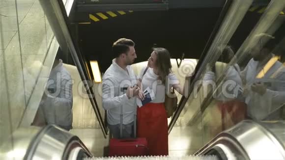 可爱的情侣在机场的自动扶梯上一个男人和他的女朋友一起旅行有白种人的人视频的预览图