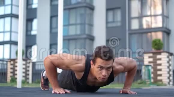 年轻男性运动员躯干裸露肖像强壮的人在地板上做俯卧撑使有力的手紧张视频的预览图
