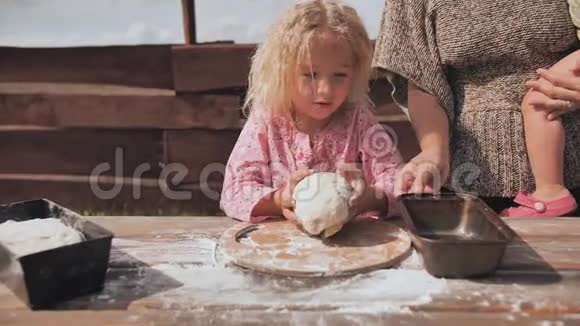 一个小女孩揉面团她的母亲支持她自制面包烘焙视频的预览图