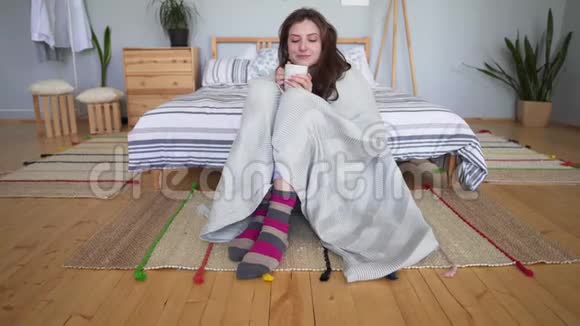 时尚概念美丽迷人的女孩坐着裹着舒适的毯子在她的卧室地板上休息视频的预览图