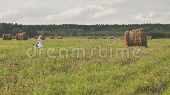 一个悲伤的小女孩正带着一架玩具飞机穿过田野背景是一堆稻草视频的预览图