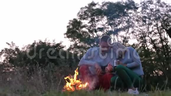 一对徒步旅行者在篝火旁取暖晚上在森林里视频的预览图
