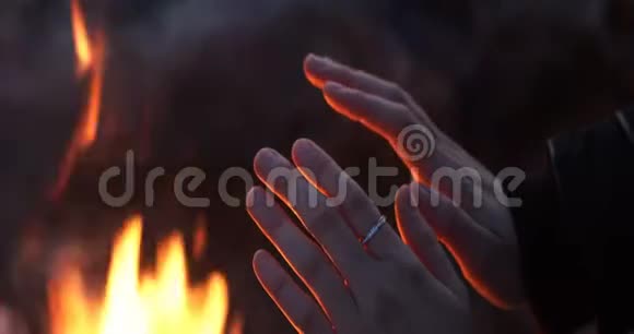 女人的手在寒冷中从火中变暖视频的预览图