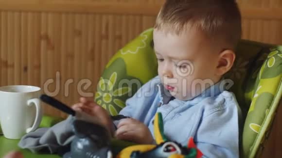 小男孩坐在厨房的高椅子上和妈妈玩手表视频的预览图
