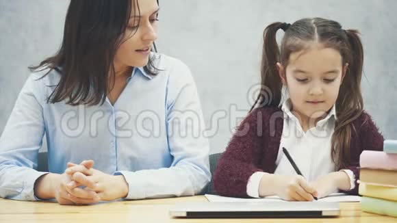 一个女学生和他的母亲坐在桌子旁写作业在这段时间里妈妈从相框里出来视频的预览图