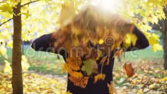 女孩在秋天公园扔树叶微笑视频的预览图