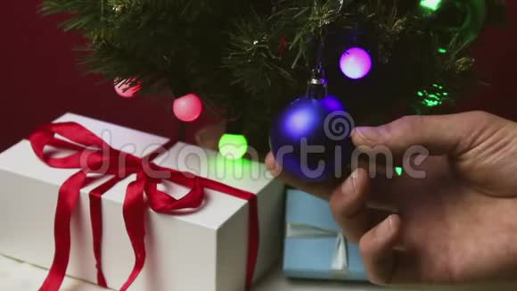 那个年轻人手伸直了圣诞树上蓝色闪闪发光的球视频的预览图