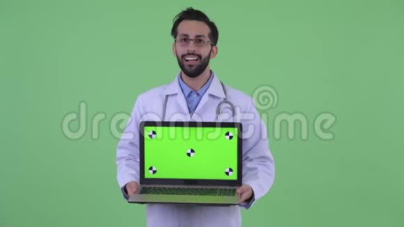 快乐的年轻留着胡子的波斯人医生一边讲着手提电脑视频的预览图