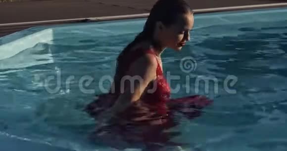 穿红衣服的美女在游泳池里散步游泳摆姿势4k视频的预览图