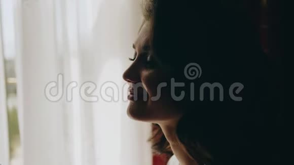 一个女孩坐在窗户附近的特写镜头造型师给女孩化妆视频的预览图