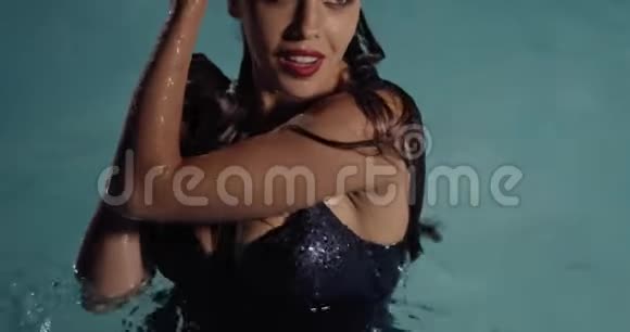 穿着黑色裙子的性感女人在游泳池里摆姿势游泳4K视频的预览图