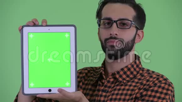 一个年轻的留着胡须的波斯时髦男人在展示数码平板电脑时说话视频的预览图