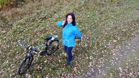 为冒险做好准备美女穿上背包坐着自行车在秋天的公园里乘飞机视频的预览图