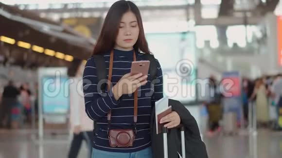年轻的女性旅行者用智能手机与机场的人交谈视频的预览图