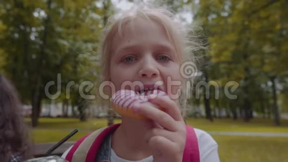 可爱的小白种人在公园里开心地吃巧克力甜甜圈视频的预览图