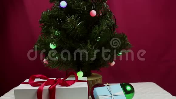 那个年轻女孩手把一个蓝色的球挂在圣诞树上女孩装饰圣诞树视频的预览图