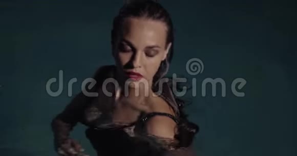 穿着黑色裙子的女人正在游泳池里游泳摆姿势化妆和口红4K视频的预览图
