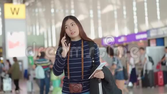 年轻的女性旅行者用智能手机与机场的人交谈视频的预览图