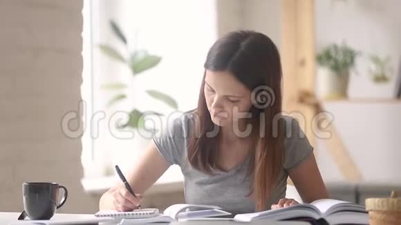 准备考试的女学生阅读笔记本上的课本视频的预览图