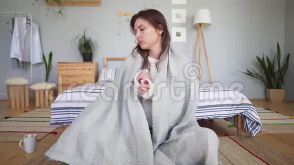 一个年轻的女人把自己裹在格子毯子里喝咖啡享受简单的东西穿着漂亮针织衣服的女孩视频的预览图