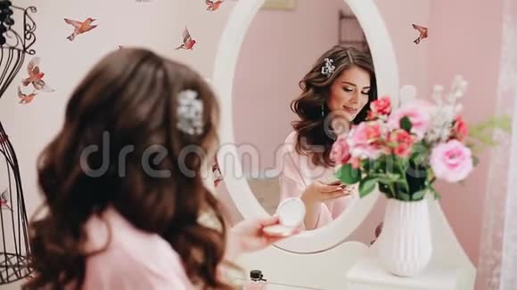 漂亮的女孩看着镜子用刷子化妆视频的预览图