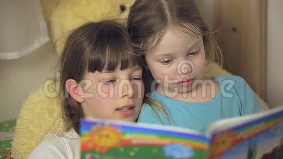 两个女孩正躺在孩子们的床上看书视频的预览图