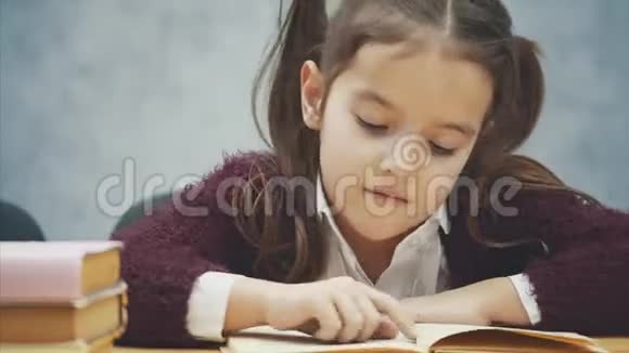 关闭一个女孩坐在灰色背景在这段时间里他仔细地读了这本书勤奋的学生视频的预览图