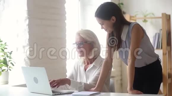 老年女性导师向新员工女孩展示在线应用程序视频的预览图