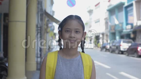 亚洲可爱女孩的肖像背包微笑站在老城镇普吉岛的小径上视频的预览图