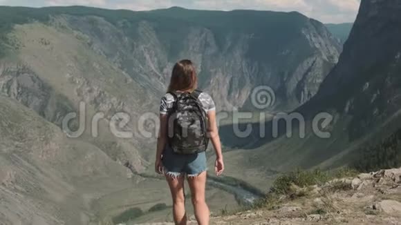 一位带着背包的女性旅行者爬上山顶举起双手感觉到一种潜水的感觉视频的预览图