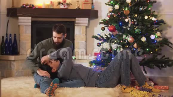 年轻漂亮的夫妇一起躺在圣诞树上新年和圣诞节的概念视频的预览图