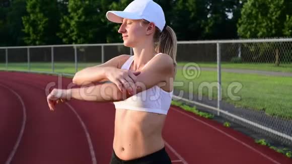 年轻的运动女子在跑道上伸展手臂视频的预览图