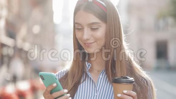 美丽的时尚年轻女性的肖像棕色头发头戴条纹衬衫使用她的智能手机视频的预览图