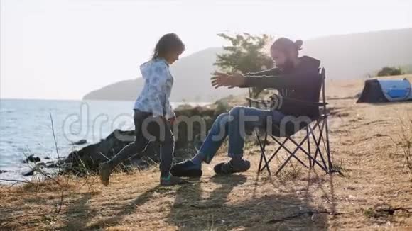 小女孩来到她的父亲身边他把她放在膝盖上户外视频的预览图