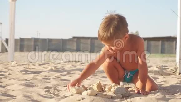 小男孩在多风的海边玩石头视频的预览图