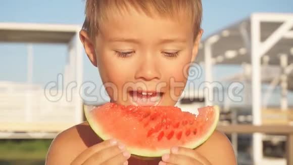 孩子们在海滩上玩沙子里的男孩吃西瓜孩子手里拿着一块绿色的瓜皮视频的预览图