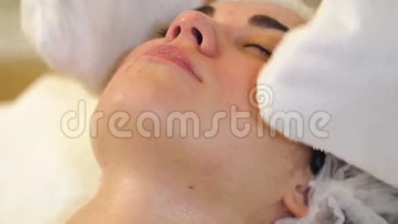 美容师用白餐巾纸在美容中心擦女孩的脸视频的预览图