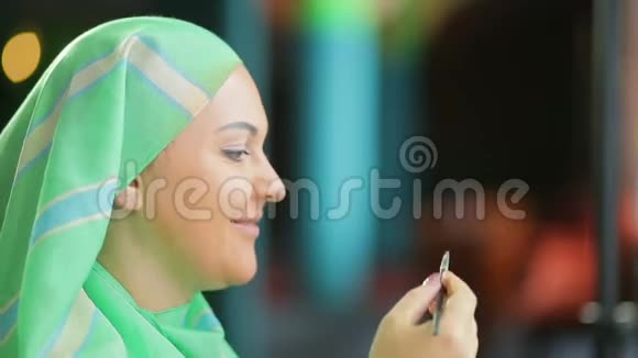 镜子前的穆斯林妇女在明亮的阴影下做眼妆视频的预览图
