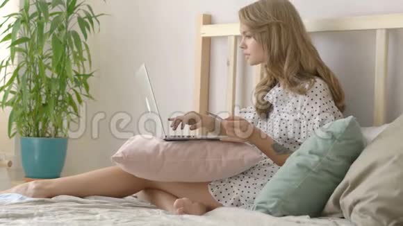 年轻女子在卧室用信用卡和笔记本电脑上网购物视频的预览图
