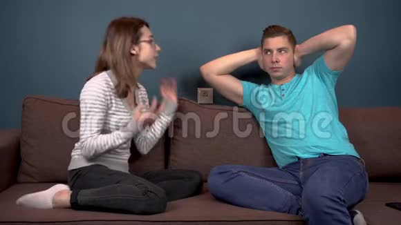 一个年轻的女人对一个年轻人大喊大叫男人用手捂住耳朵以免听到女人的声音坐在上面视频的预览图