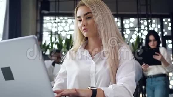 漂亮的年轻有目标的女商人微笑着在现代办公室的电脑前工作视频的预览图