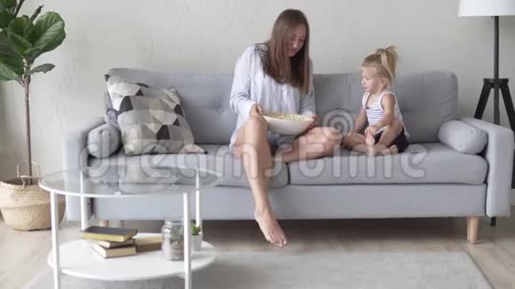 妈妈和女儿坐在他们的睡衣沙发上视频的预览图
