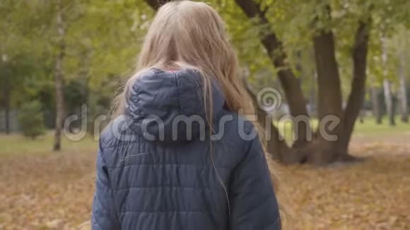 白种人十几岁的女孩走在秋天的公园里回头看着相机戴眼镜的可爱少年视频的预览图