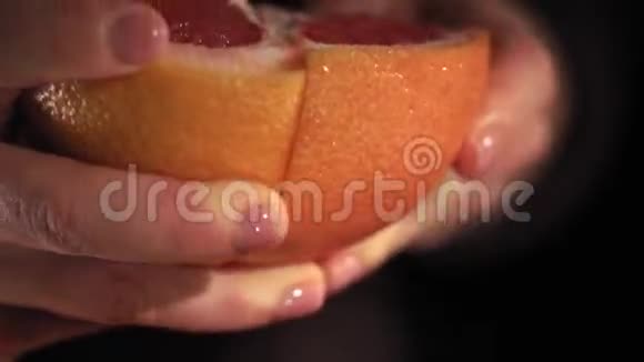 女性手清洁葡萄柚黑暗的背景低键视频的预览图