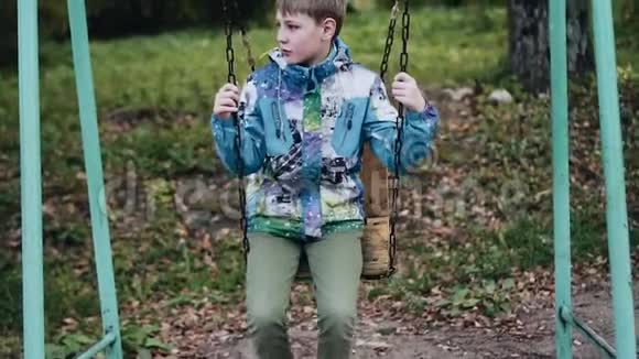 一个穿夹克的孩子在秋千上摇摆连锁秋千正面观点视频的预览图