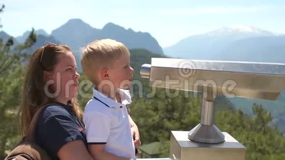 母亲和儿子透过观察甲板上的硬币望远镜视频的预览图