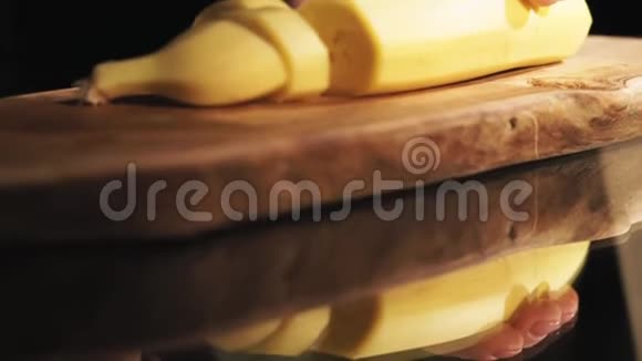 女性用刀子在木切割板上切香蕉视频的预览图
