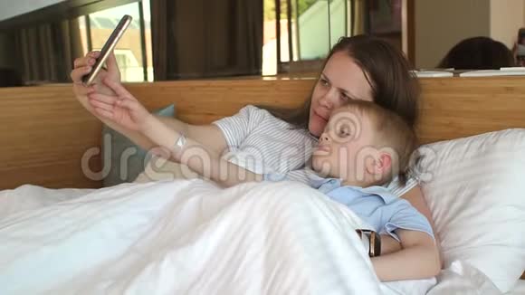 一位母亲和一个小儿子的特写在床上打电话自拍视频的预览图