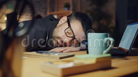 当同事们工作时精疲力竭的经理晚上睡在办公室的桌子上视频的预览图