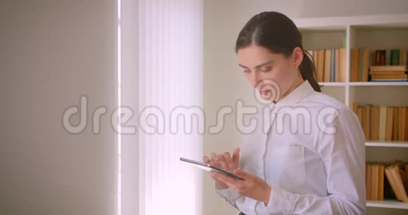 年轻有魅力的高加索女商人用平板电脑拍摄了一幅特写照片照片上的人正站在办公室里视频的预览图